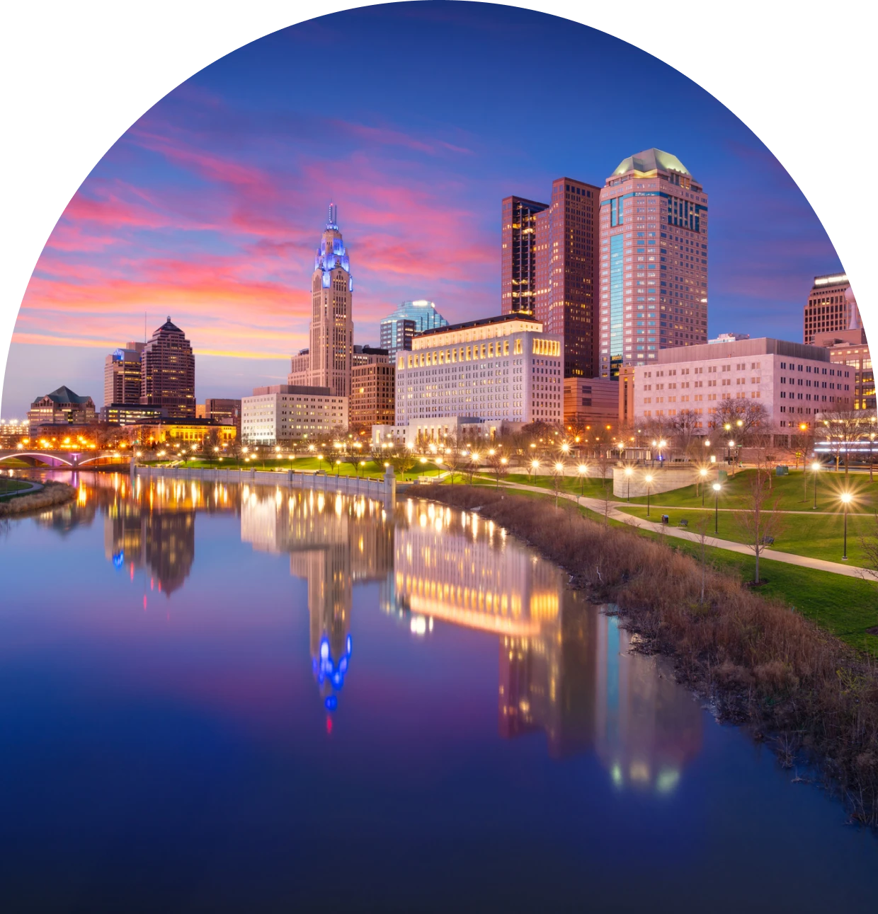 City skyline at sunset with river reflection.