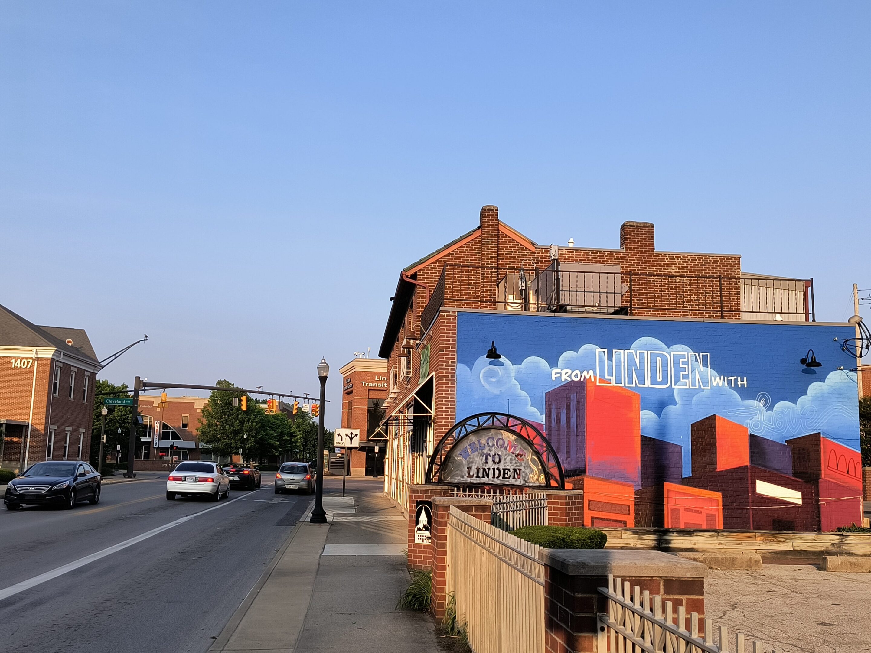 Street view with colorful murals on brick buildings under a clear sky.