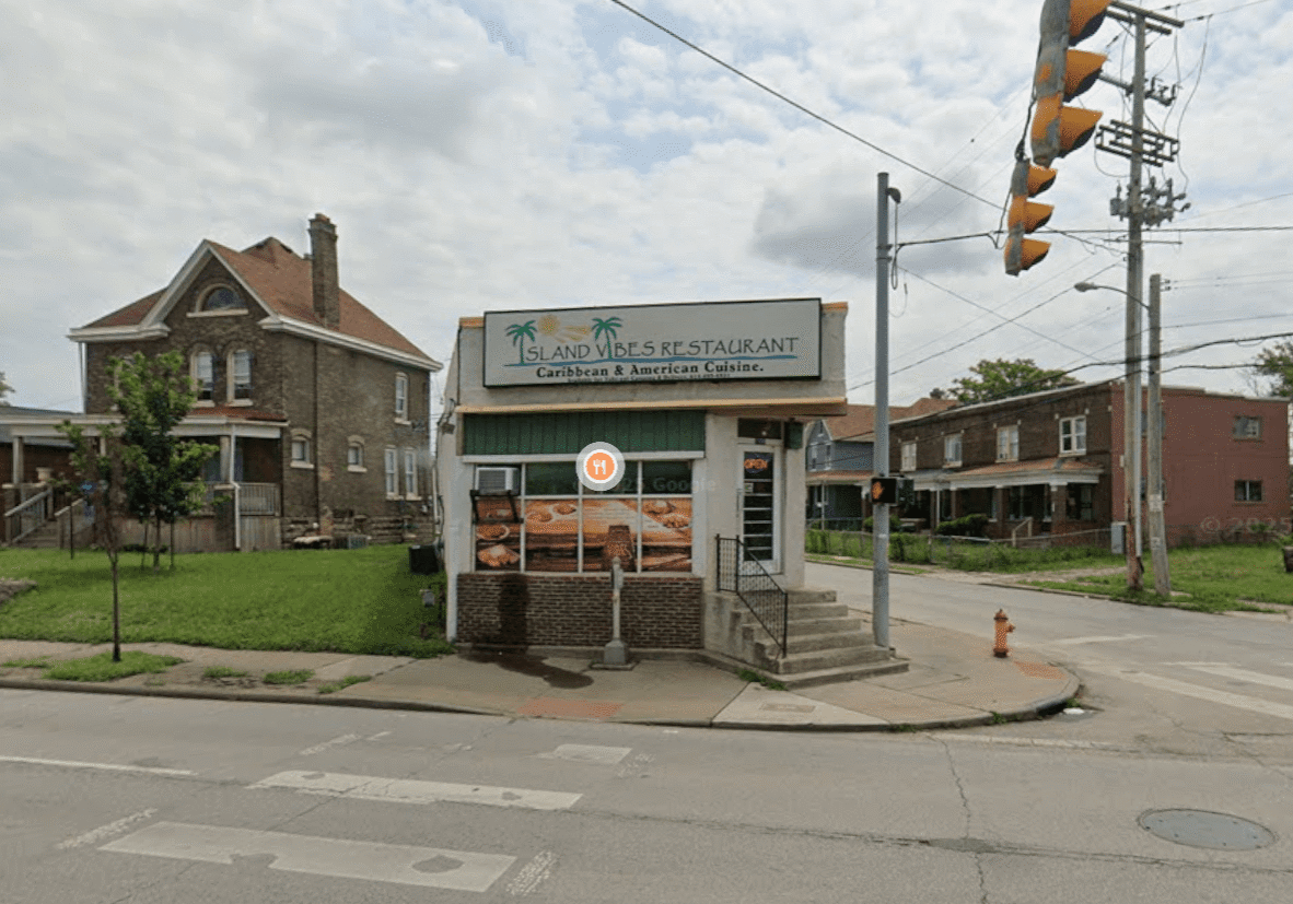 Small corner convenience store with a worn exterior and fenced entrance.