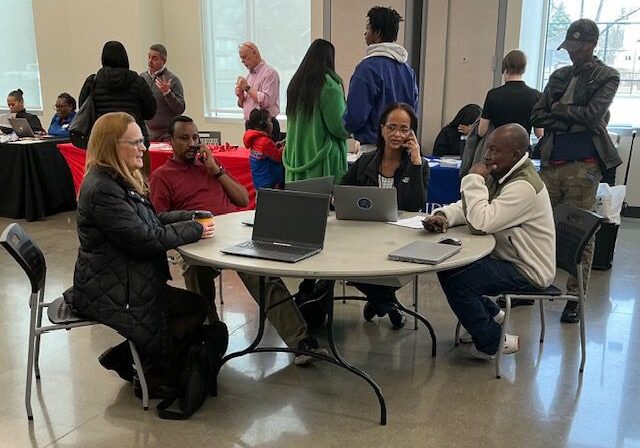 People engaged in a casual meeting around a table with laptops.