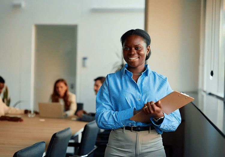 Smiling woman holding clipboard in office.